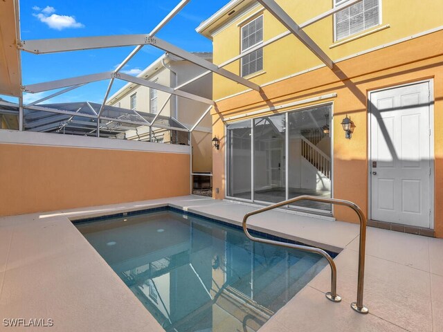 view of pool with glass enclosure and a patio