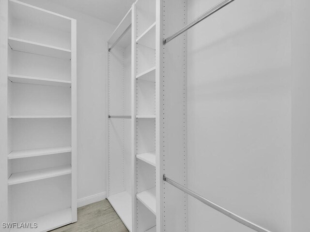 walk in closet with light hardwood / wood-style flooring