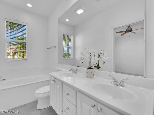 bathroom featuring a bathing tub, vanity, a wealth of natural light, and toilet