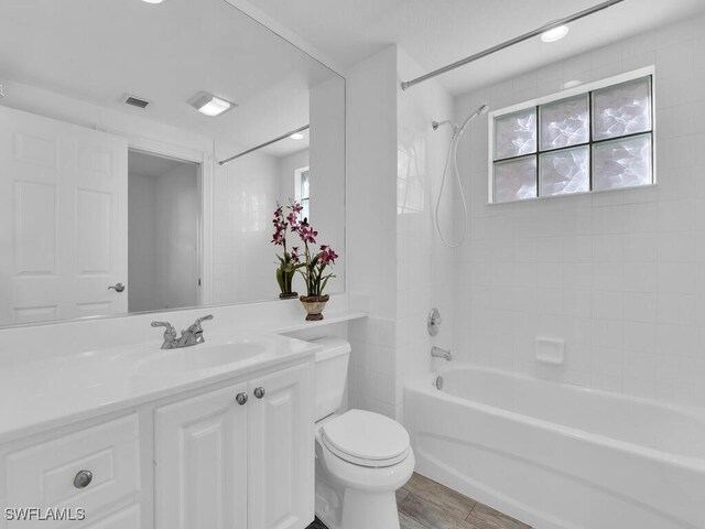 full bathroom featuring tiled shower / bath combo, toilet, vanity, and a healthy amount of sunlight