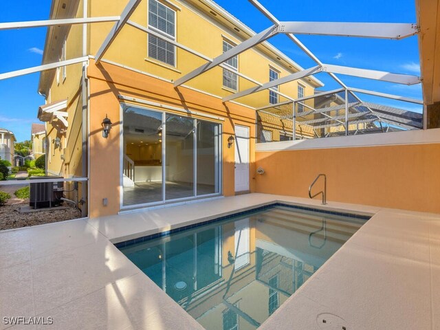 view of pool featuring glass enclosure, central air condition unit, and a patio