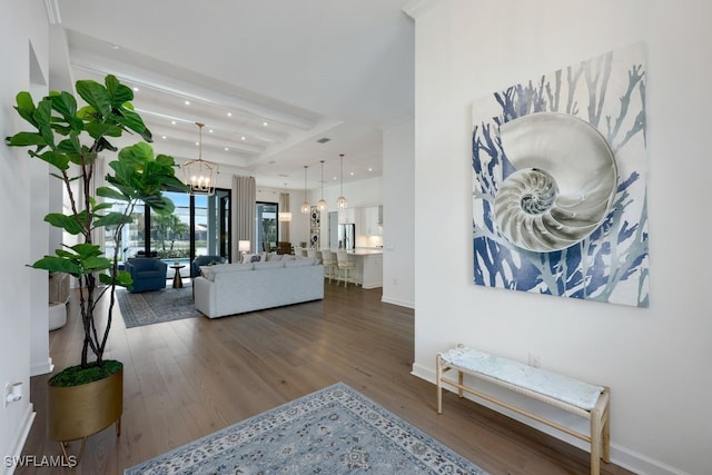 living room featuring hardwood / wood-style floors, an inviting chandelier, and a raised ceiling