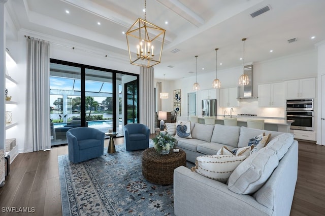 living room with dark wood-type flooring, ornamental molding, and an inviting chandelier