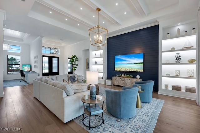 living room featuring french doors, beam ceiling, hardwood / wood-style floors, an inviting chandelier, and built in features