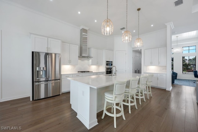 kitchen featuring white cabinetry, stainless steel appliances, and wall chimney range hood