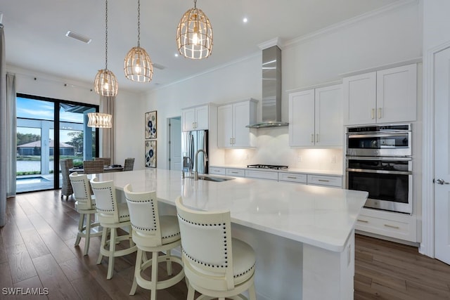 kitchen featuring white cabinetry, wall chimney exhaust hood, sink, and an island with sink