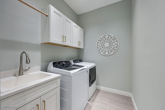 clothes washing area featuring cabinets, sink, and washing machine and clothes dryer