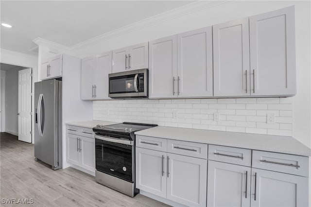 kitchen featuring appliances with stainless steel finishes, white cabinets, ornamental molding, and light hardwood / wood-style flooring