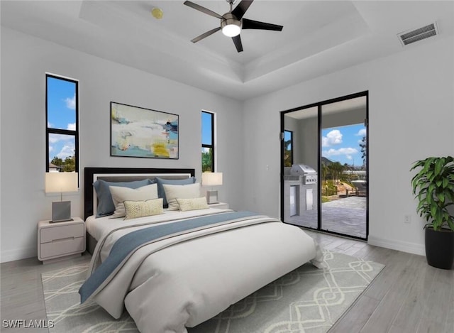 bedroom featuring light wood-type flooring, multiple windows, ceiling fan, and access to outside