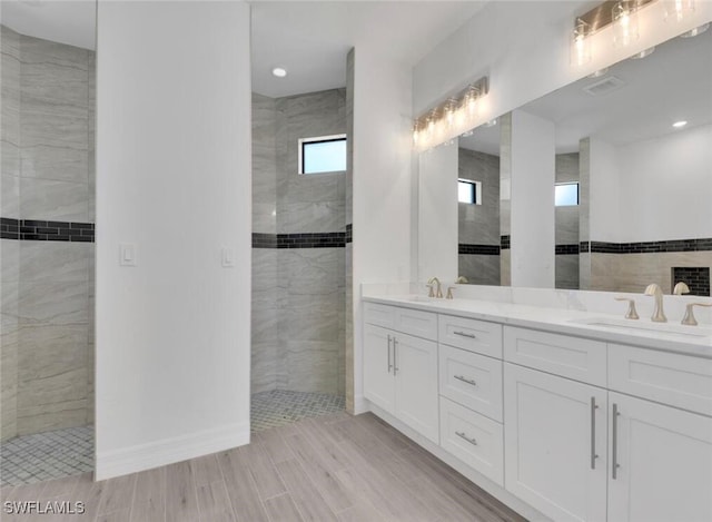 bathroom with tile walls, vanity, and tiled shower