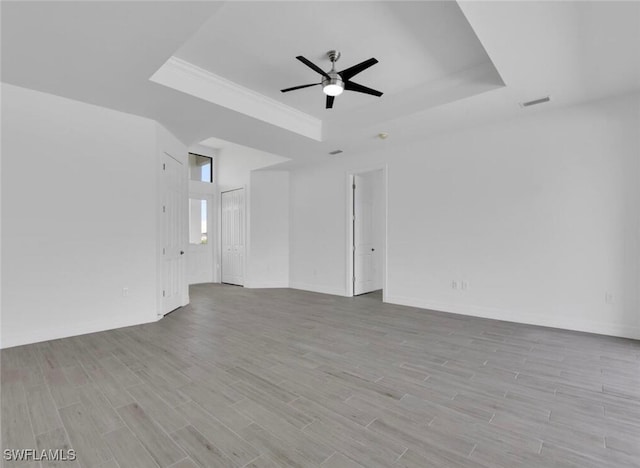 spare room featuring ceiling fan, a raised ceiling, and light wood-type flooring