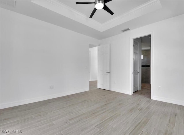 unfurnished bedroom featuring crown molding, a tray ceiling, light wood-type flooring, and ceiling fan