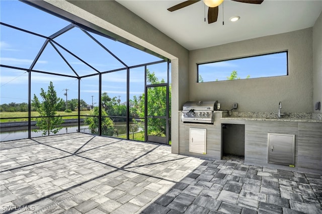 view of patio with ceiling fan, area for grilling, a grill, sink, and glass enclosure