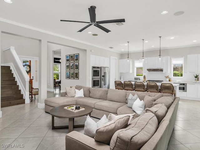 living room with ornamental molding, light tile patterned floors, and ceiling fan