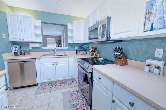 kitchen featuring stainless steel appliances, sink, light tile patterned flooring, and white cabinets