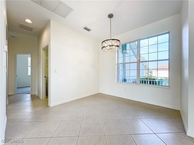 spare room featuring a notable chandelier and light tile patterned floors