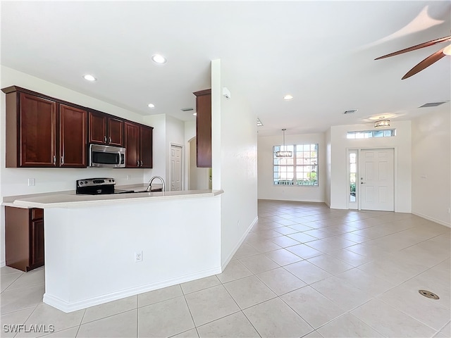 kitchen with kitchen peninsula, stainless steel appliances, sink, light tile patterned floors, and ceiling fan with notable chandelier