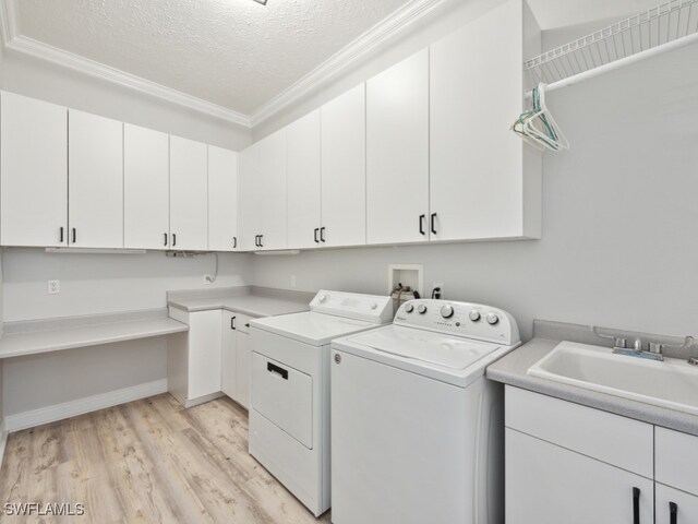 clothes washing area with light hardwood / wood-style floors, washer and dryer, crown molding, sink, and a textured ceiling