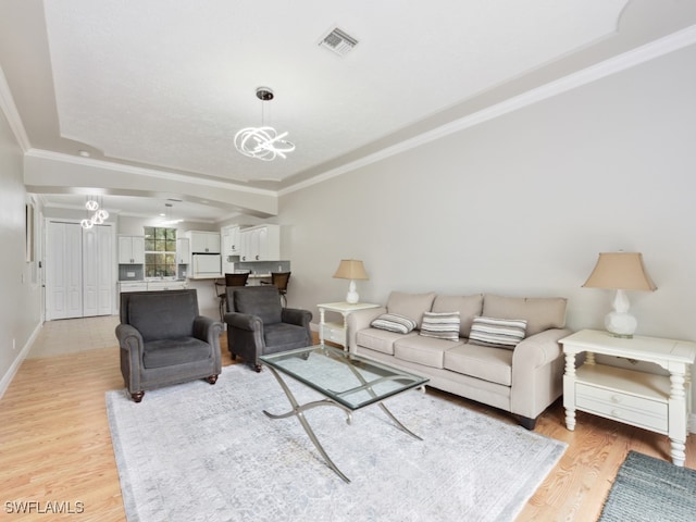 living room featuring ornamental molding, light wood-type flooring, and a notable chandelier