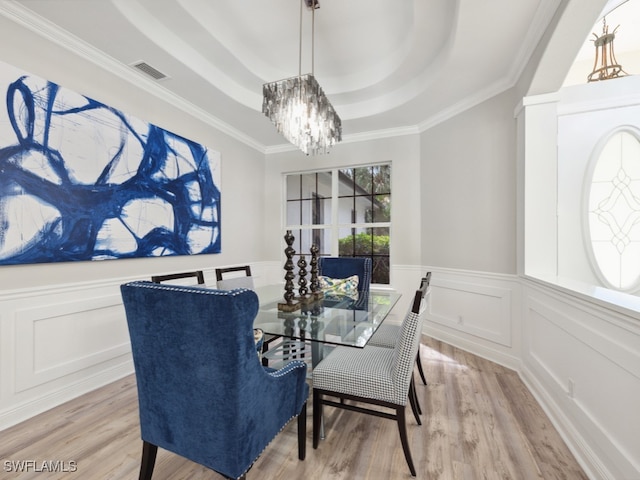 dining room featuring ornamental molding, a tray ceiling, hardwood / wood-style floors, and an inviting chandelier