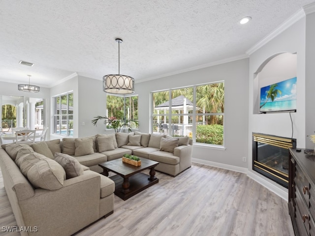 living room featuring a textured ceiling, crown molding, a chandelier, and light hardwood / wood-style flooring