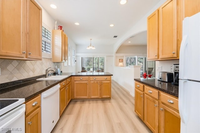 kitchen with sink, kitchen peninsula, white appliances, decorative light fixtures, and light hardwood / wood-style flooring