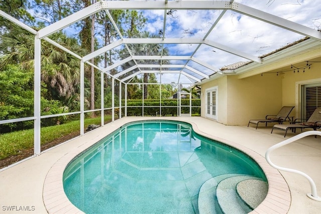 view of pool featuring glass enclosure and a patio