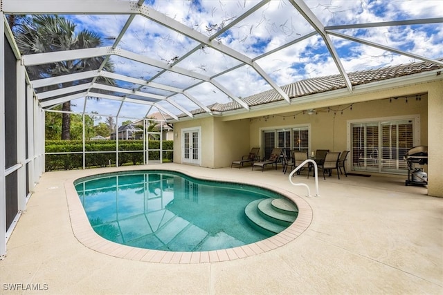 view of swimming pool featuring ceiling fan, area for grilling, a lanai, and a patio area