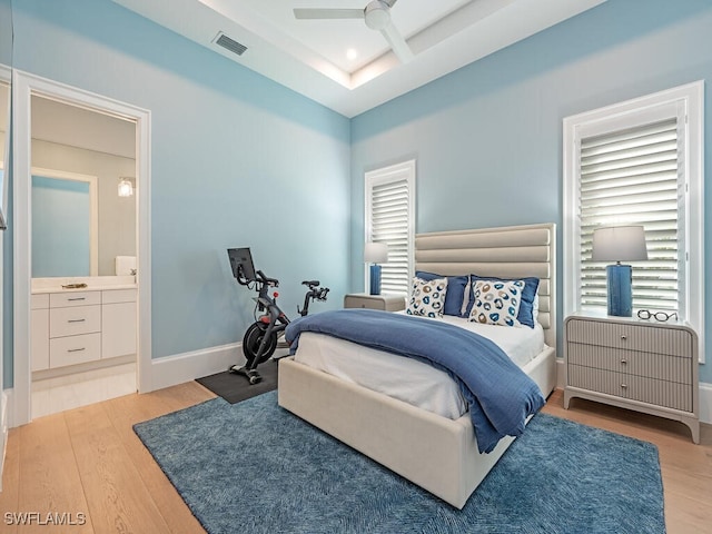 bedroom with light hardwood / wood-style flooring, ensuite bathroom, and ceiling fan