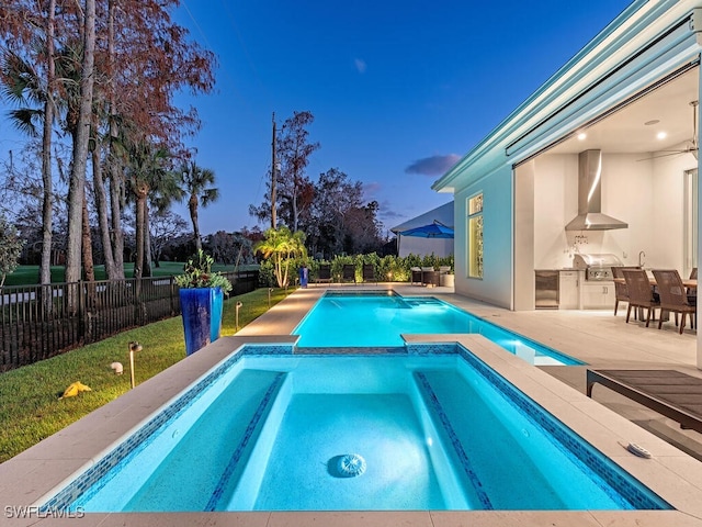 pool at dusk with an in ground hot tub, a patio, and area for grilling