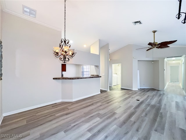 unfurnished living room featuring vaulted ceiling, ceiling fan with notable chandelier, crown molding, and wood-type flooring