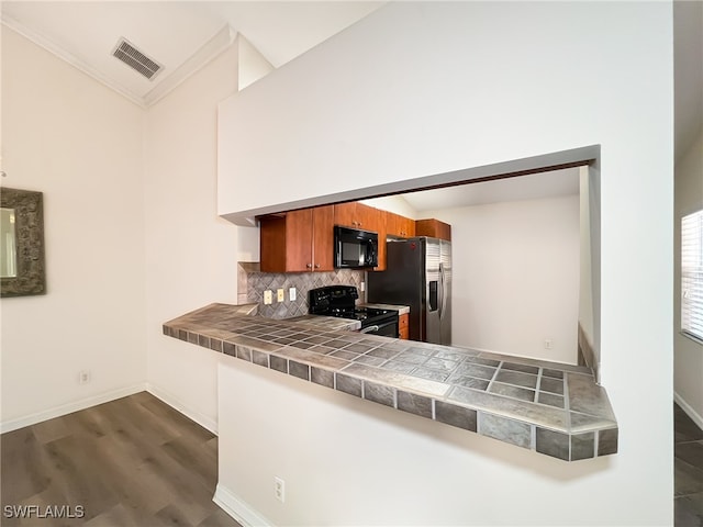 kitchen featuring black appliances, tasteful backsplash, dark hardwood / wood-style floors, kitchen peninsula, and tile countertops