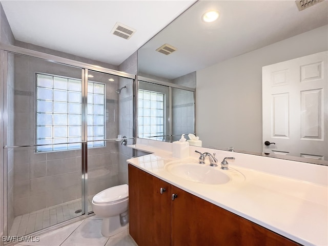 bathroom with vanity, toilet, a shower with shower door, and tile patterned flooring