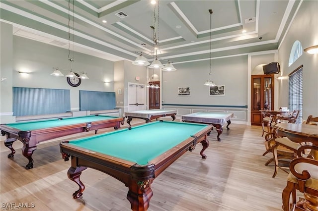 recreation room with crown molding, coffered ceiling, light hardwood / wood-style flooring, and a high ceiling