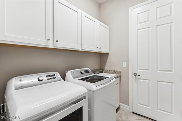 laundry area with washer and clothes dryer, light tile patterned floors, cabinets, and sink