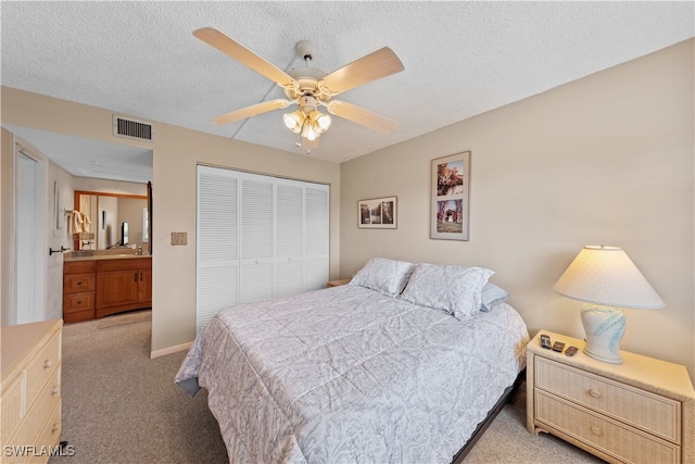 bedroom with a textured ceiling, light colored carpet, a closet, and ceiling fan