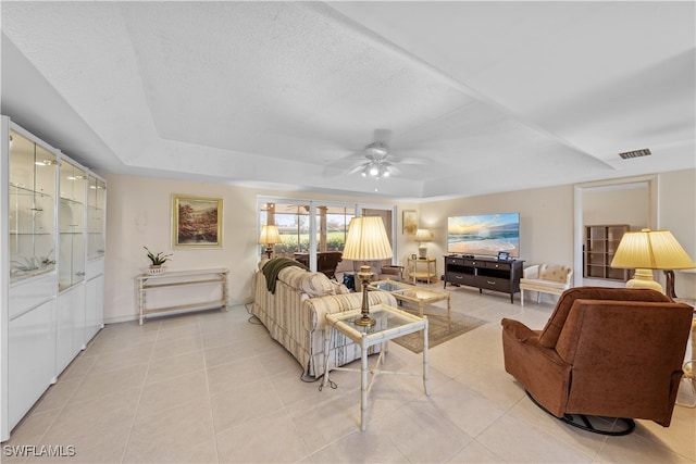 living room featuring a tray ceiling, light tile patterned floors, and ceiling fan