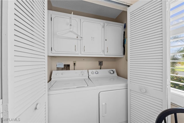 clothes washing area with a textured ceiling, cabinets, and washing machine and clothes dryer