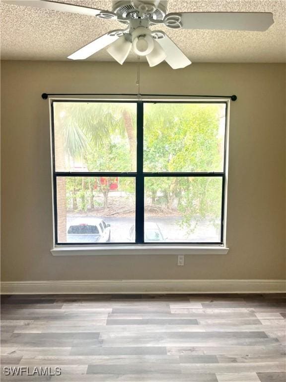 spare room featuring ceiling fan, light hardwood / wood-style flooring, and a textured ceiling