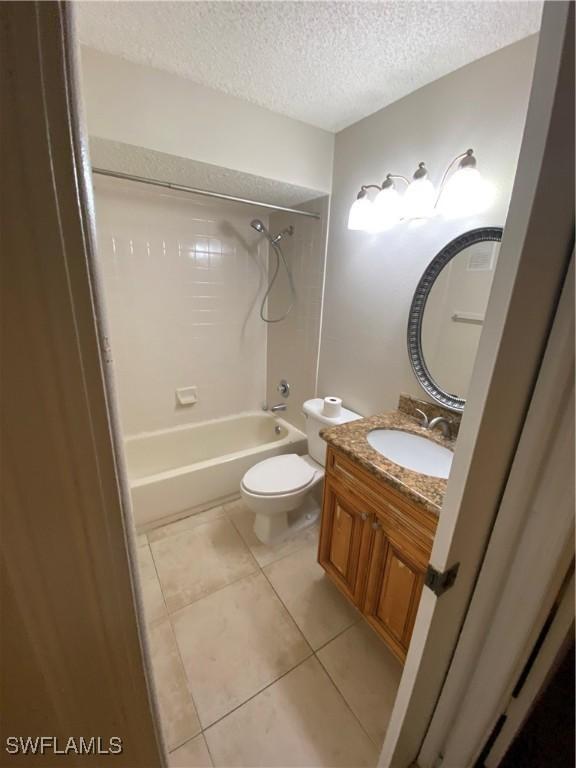 full bathroom featuring tile patterned floors, shower / bathing tub combination, a textured ceiling, toilet, and vanity