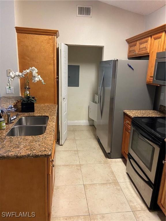 kitchen with sink, black electric range oven, lofted ceiling, stone countertops, and light tile patterned flooring