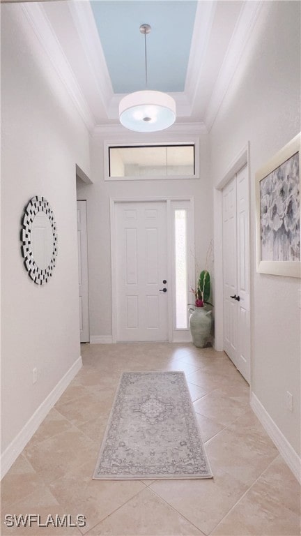 foyer entrance with a raised ceiling, ornamental molding, a towering ceiling, and light tile patterned floors