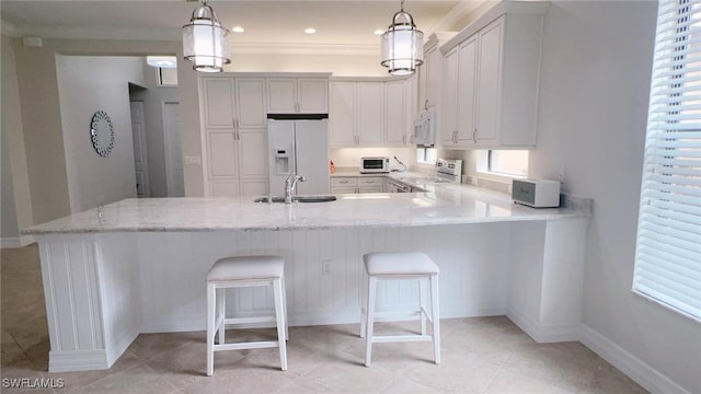 kitchen with white appliances, decorative light fixtures, and a breakfast bar area