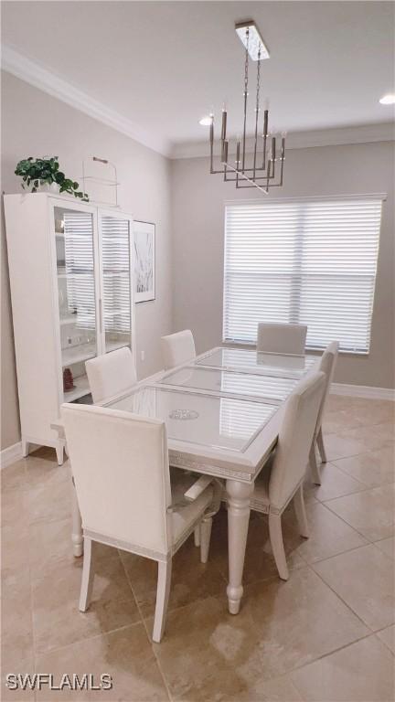 tiled dining room with a healthy amount of sunlight, ornamental molding, and an inviting chandelier