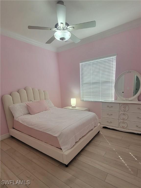 bedroom featuring crown molding, light wood-type flooring, and ceiling fan