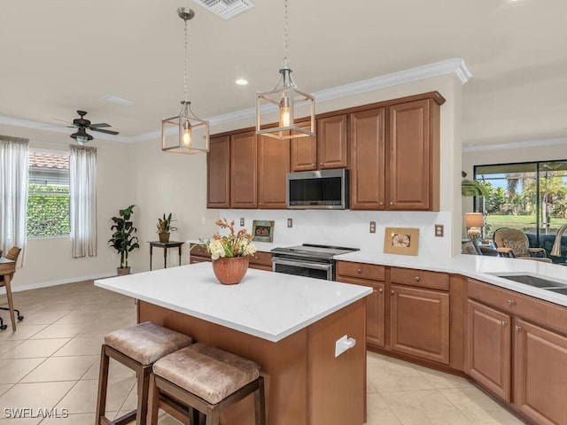 kitchen featuring stainless steel appliances, crown molding, light countertops, pendant lighting, and a sink