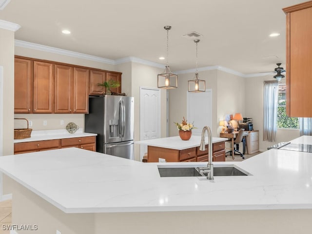 kitchen with a sink, a kitchen island, visible vents, brown cabinets, and stainless steel fridge