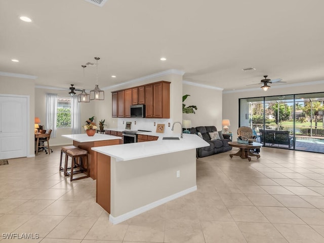 kitchen featuring stainless steel appliances, a sink, a kitchen breakfast bar, light countertops, and brown cabinets