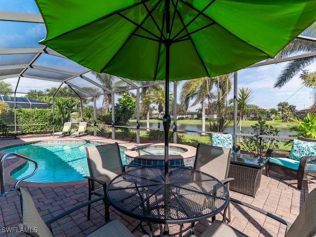 view of swimming pool featuring a water view, a patio area, a pool with connected hot tub, and glass enclosure