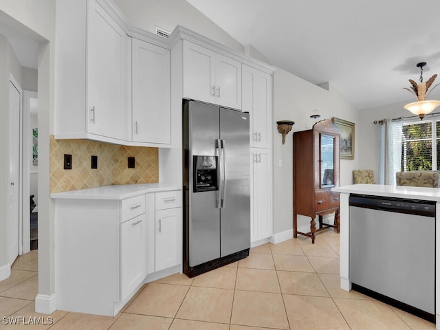 kitchen with white cabinets, vaulted ceiling, light tile patterned floors, and appliances with stainless steel finishes